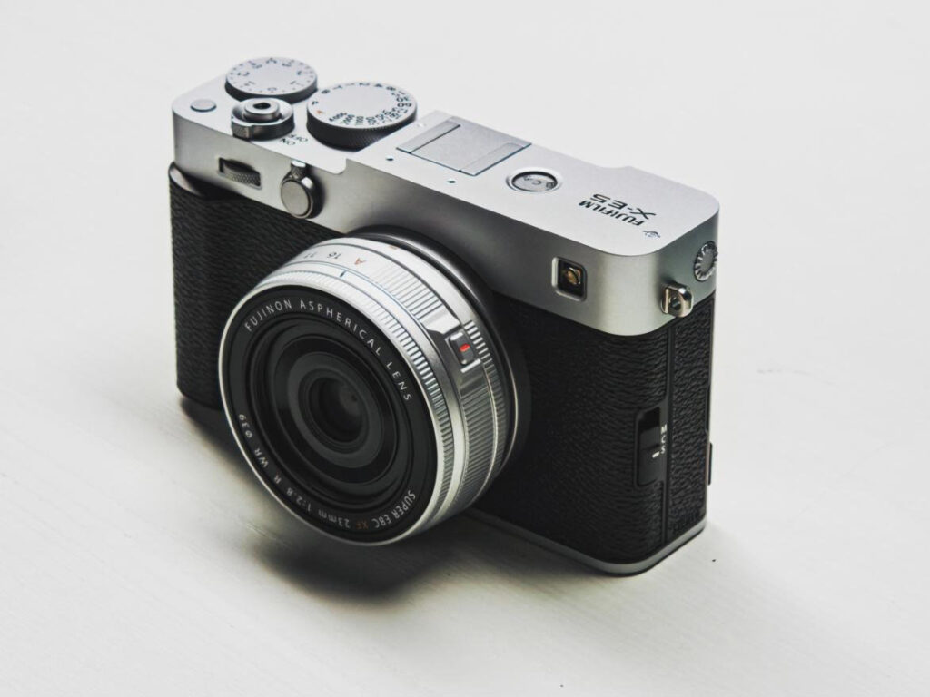 A silver Fujifilm X-E5 with the silver version of the Fuji 23mm f/2.8 WR pancake lens