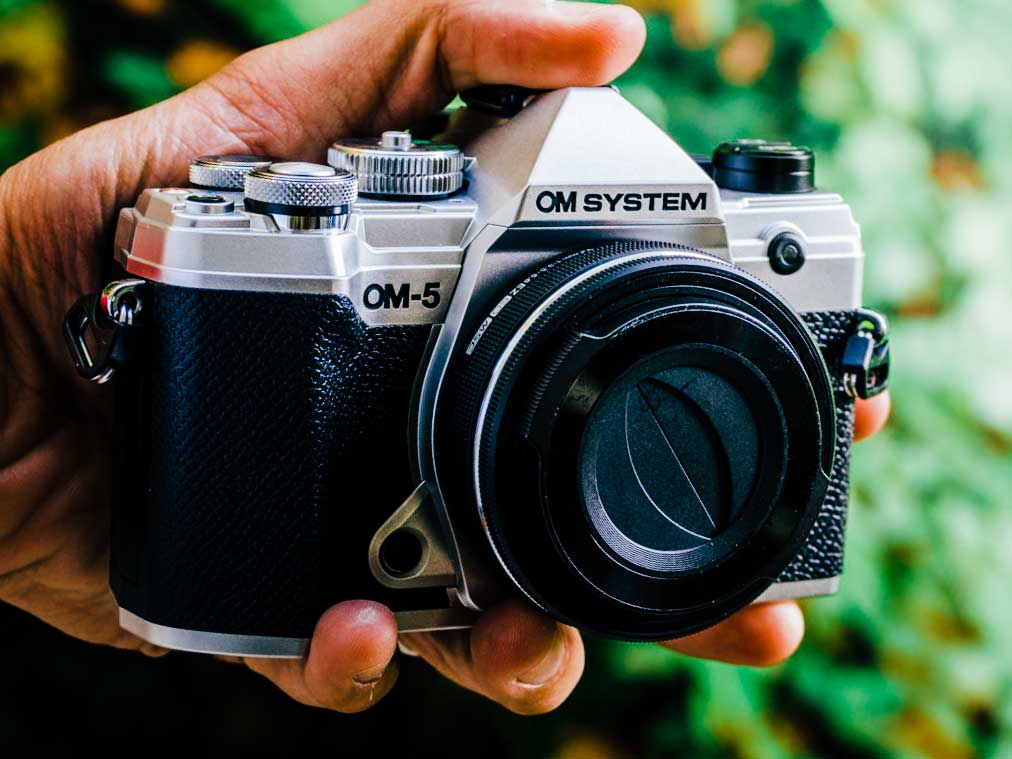 Olympus OM-System OM-5 camera in silver with the 14-42mm pancake lens